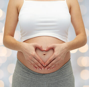 close up of pregnant woman touching her bare tummy